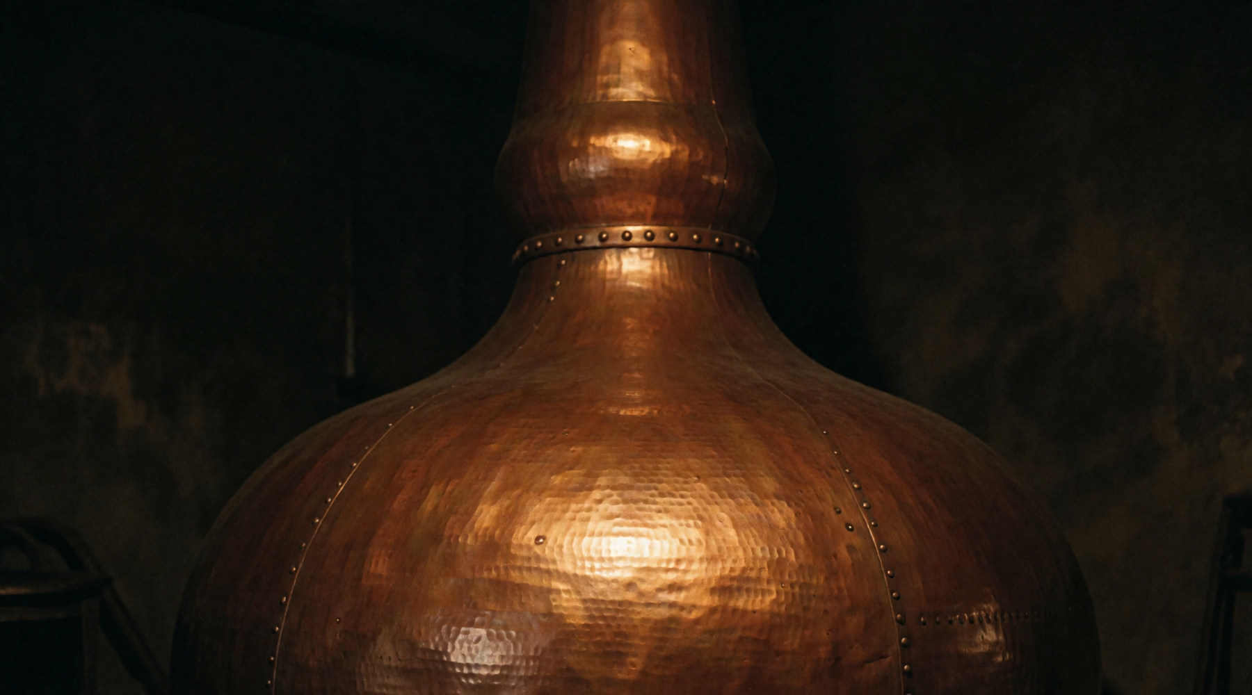 A copper pot still in a dark stillhouse.